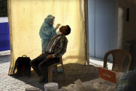 A health worker takes a swab test at a COVID-19 testing center in New Delhi, India, Monday, April 27, 2020. India’s main medical research organization has cancelled orders to procure rapid antibody test kits from two Chinese companies after quality issues and controversies over its price. (AP Photo/Manish Swarup)