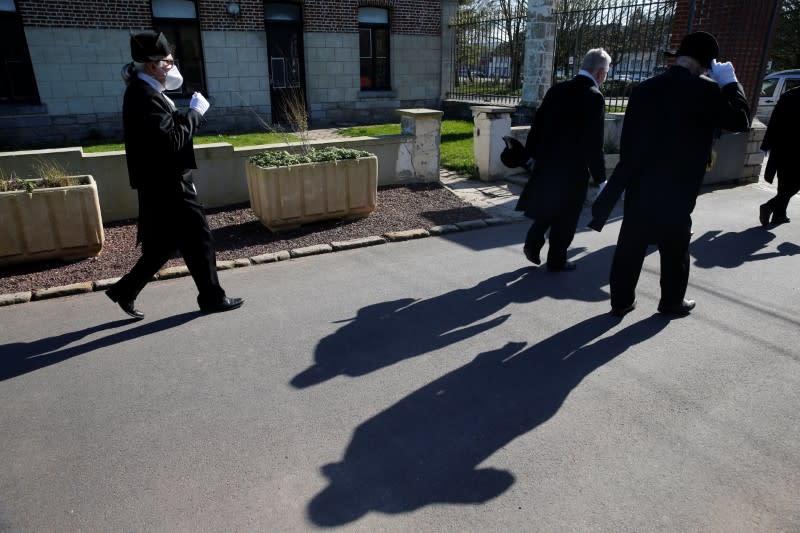 Members of the Charitable Brotherhood, which first formed during the plague 800 years ago, leave after a burial ceremony in Bethune