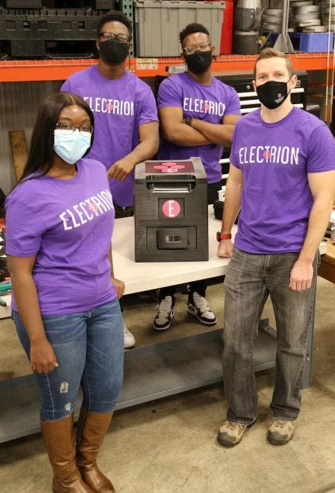 The Electrion team (comprised of students from Ohio State) stands next to their wireless battery pack alternative to gas generators at tailgating events.