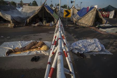 Anti-government protesters sleep beside tents set up in front of the Parliament house in the Red Zone during the Revolution March in Islamabad September 9, 2014. REUTERS/Zohra Bensemra