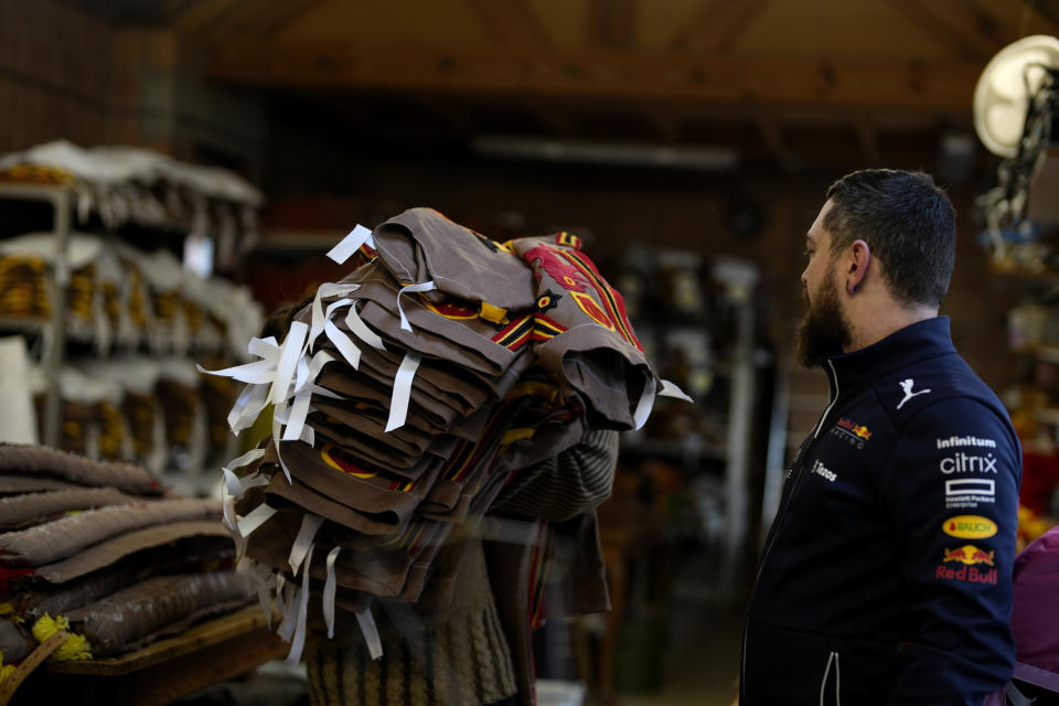 Quentin Kersten watches as a worker walks by with a stack of costumes in the family costume workshop in Binche, Belgium, Wednesday, Feb. 1, 2023. After a COVID-imposed hiatus, artisans are putting finishing touches on elaborate costumes and floats for the renowned Carnival in the Belgian town of Binche, a tradition that brings together young and old and is a welcome moment of celebration after a rough few years. (AP Photo/Virginia Mayo)