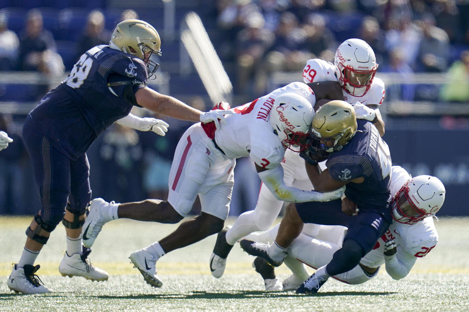 Navy fullback Daba Fofana, center, is tackled by Houston linebackers Donavan Mutin (3), Treylin Payne (29) and Jamal Morris (25) during the first half of an NCAA college football game, Saturday, Oct. 22, 2022, in Annapolis, Md. Navy's Kip Frankland, left, tries to help block on the play. (AP Photo/Julio Cortez)