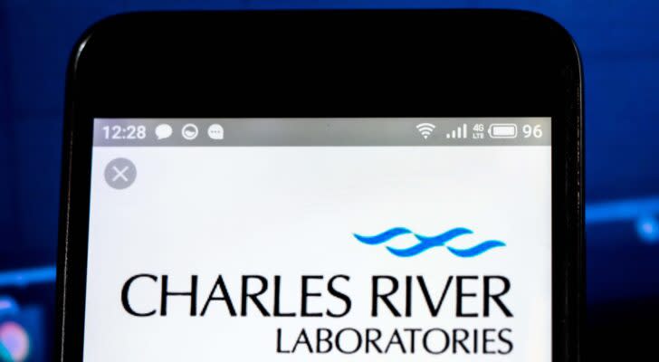 The logo for Charles River Laboratories (CRL) displayed on a smartphone with a blue stock chart in the background.
