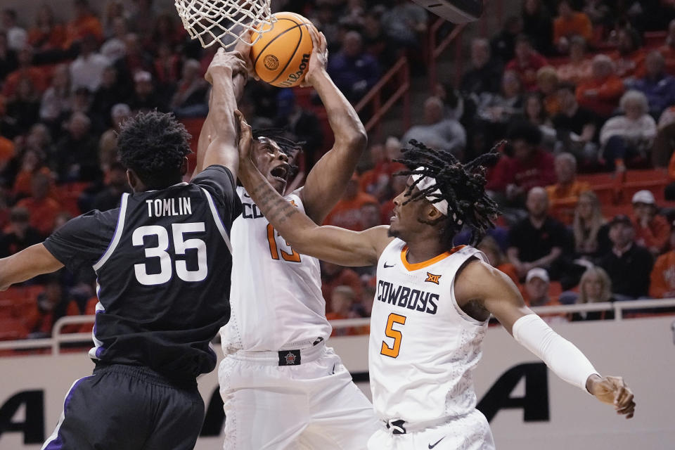 Oklahoma State guard Quion Williams (13) is fouled by Kansas State forward Nae'Qwan Tomlin (35) as he grabs a rebound in front of teammate Caleb Asberry (5) in the first half of an NCAA college basketball game, Saturday, Feb. 25, 2023, in Stillwater, Okla. (AP Photo/Sue Ogrocki)