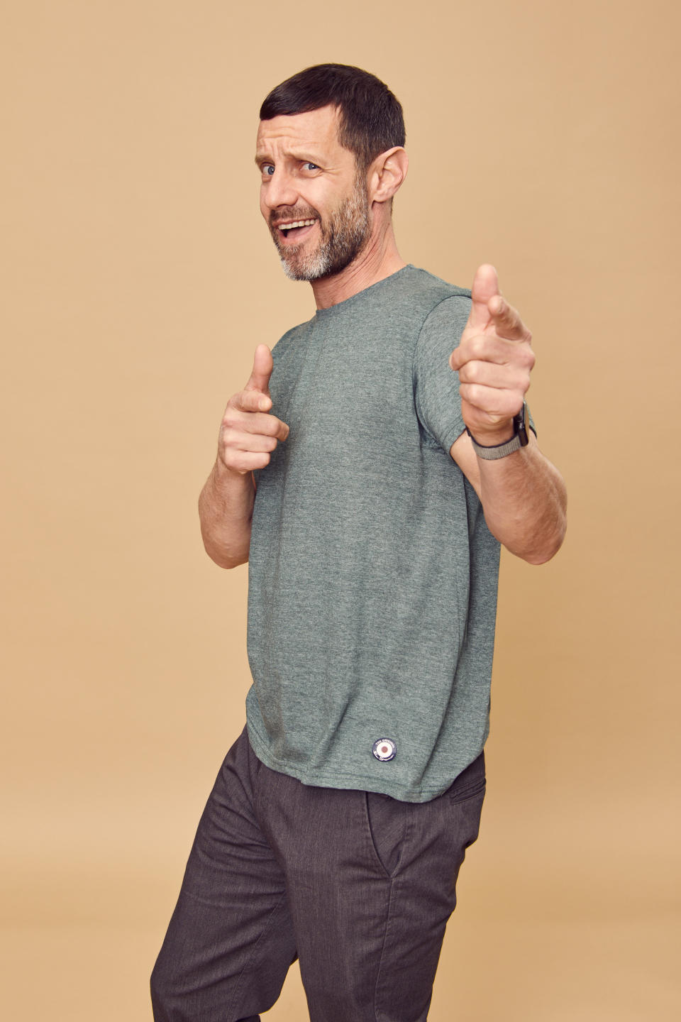 An adult Omri pointing at the camera as he smiles.