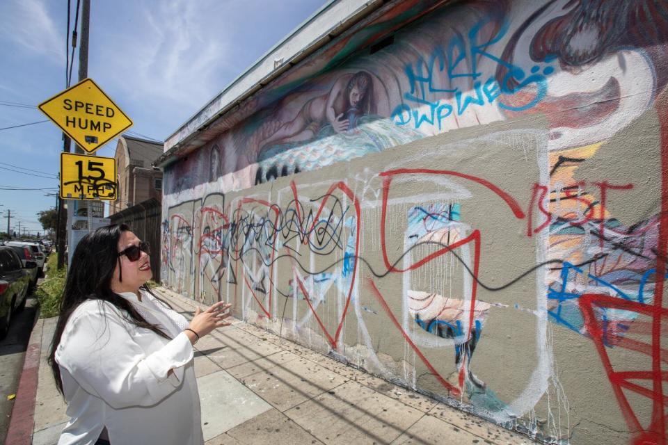 A woman looks at a graffitied wall.