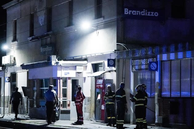 Firemen and carabinieri stand at the train station of Brandizzo where five railway workers died after being hit by a train during overnight maintenance.