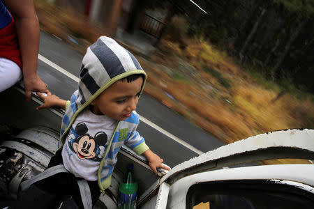 A Honduran migrant child is sitting on the back of the truck, after hitchhiking to get into the Agua Caliente border and hoping to cross into Guatemala and join a caravan trying to reach the U.S, in the municipality of Ocotepeque, Honduras October 17, 2018. REUTERS/Jorge Cabrera