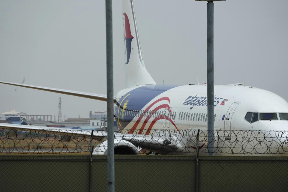 A Malaysian airplane lands at Phnom Penh International Airport in Phnom Penh, Cambodia, Tuesday, April 11, 2023, before transporting Japanese citizens who were taken into custody on suspicion of running phone scam. Over a dozen of Japanese men detained in Cambodia in January on suspicion of taking part in phone and online scams were deported to their homeland on Tuesday, police said. (AP Photo/Heng Sinith)