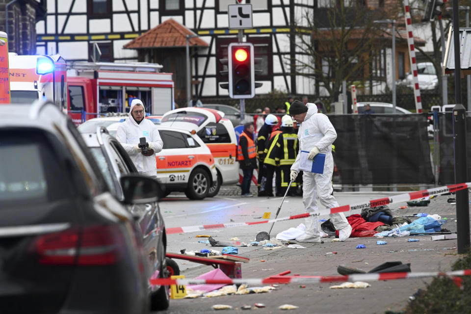 Police and rescue workers stand next to the scene of the accident with a car that is said to have crashed into a carnival parade in Volkmarsen, central Germany, Monday, Feb. 24, 2020. Several people have been injured, according to the police. The driver had been arrested by the police. (Uwe Zucchi/dpa via AP)