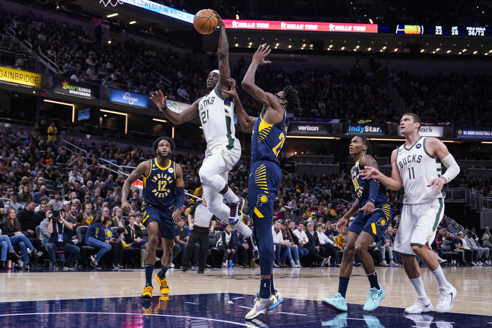 Milwaukee Bucks guard Jrue Holiday (21) scores over Indiana Pacers forward Serge Ibaka (25) during the second half of an NBA basketball game in Indianapolis, Wednesday, March 29, 2023. (AP Photo/Michael Conroy)