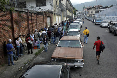 People line up outside a supermarket next to motorists queuing for gas near a gas station of the Venezuelan state-owned oil company PDVSA in San Cristobal, Venezuela November 10, 2018. REUTERS/Carlos Eduardo Ramirez