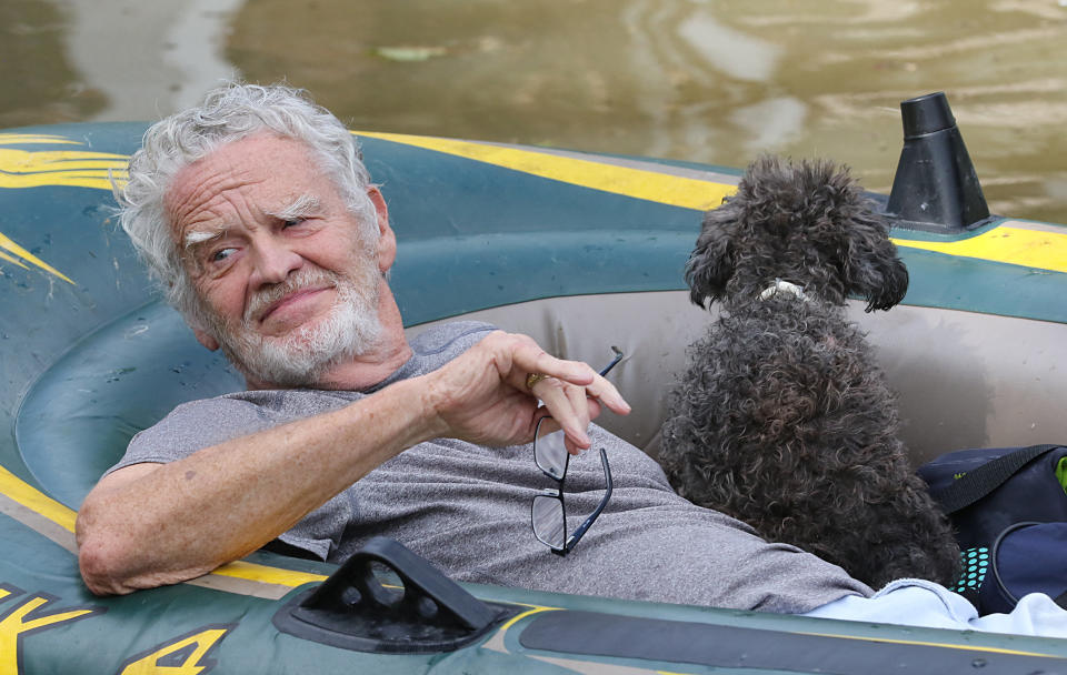 A man and his dog evacuate the flood waters in Lakeside Estate by boat in Houston, Texas on August 30, 2017. Monster storm Harvey made landfall again Wednesday in Louisiana, evoking painful memories of Hurricane Katrina's deadly strike 12 years ago, as time was running out in Texas to find survivors in the raging floodwaters. / AFP PHOTO / Thomas B. Shea        (Photo credit should read THOMAS B. SHEA/AFP/Getty Images)