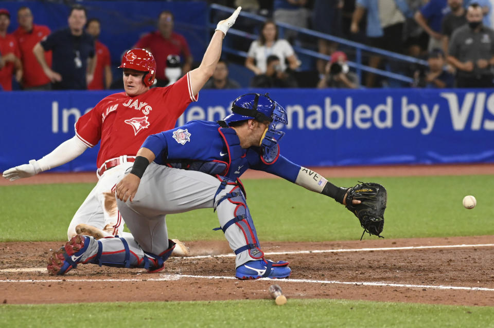 Toronto Blue Jays third baseman Matt Chapman, left, slides safely into home plate ahead of a tag by Chicago Cubs catcher Willson Contreras, right, on a walk-off single by Danny Jansen in the eleventh inning of a baseball game in Toronto on Monday, Aug. 29, 2022. (Jon Blacker/The Canadian Press via AP)