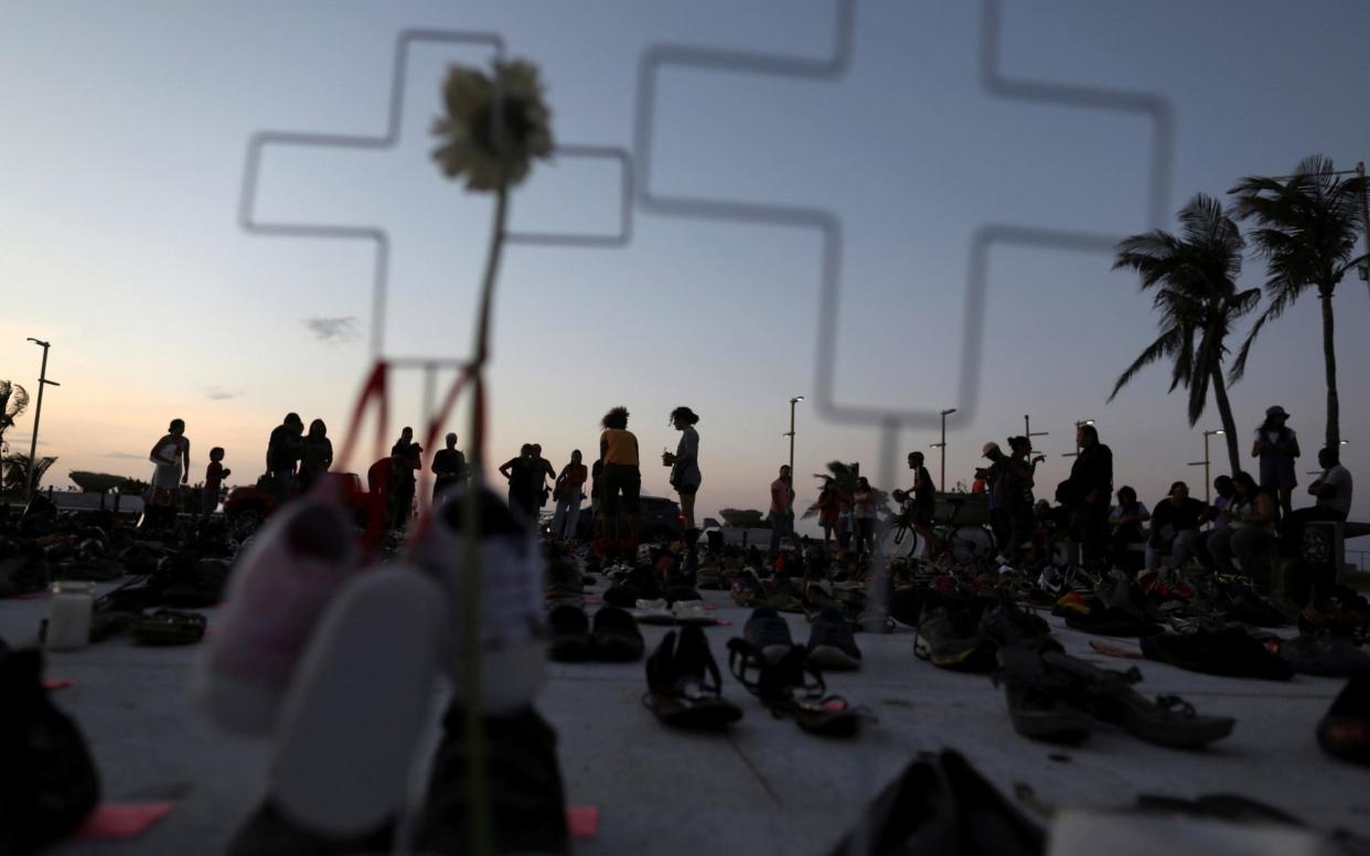 People stand among hundreds of pairs of shoes displayed at the Capitol to pay tribute to Hurricane Maria's victims in San Juan - REUTERS