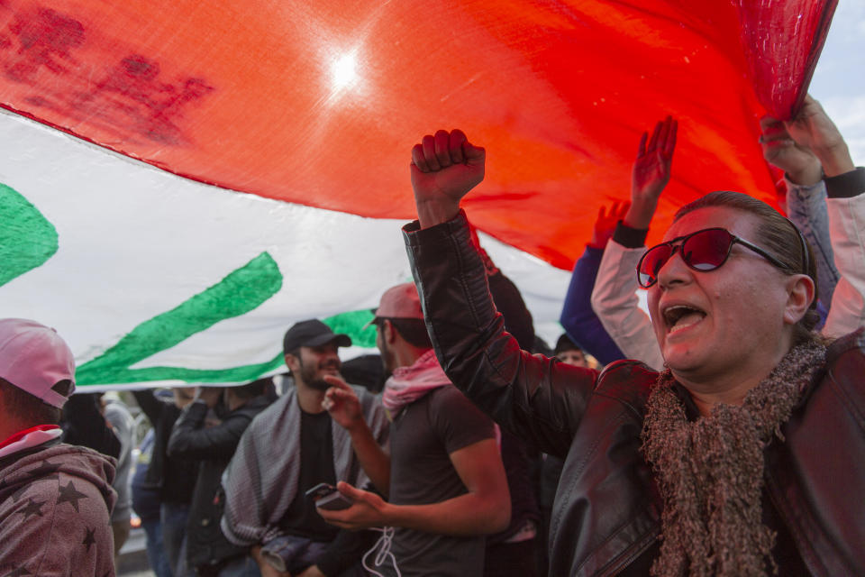 Anti government protesters chant anti Iran and anti U.S. slogans under a big Iraqi flag that they carry during the ongoing protests in Tahrir square, Baghdad, Iraq, Friday, Jan. 10, 2020. (AP Photo/Nasser Nasser)