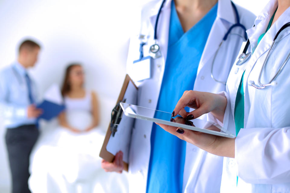 Two physicians standing beside each other with one holding a touchscreen tablet