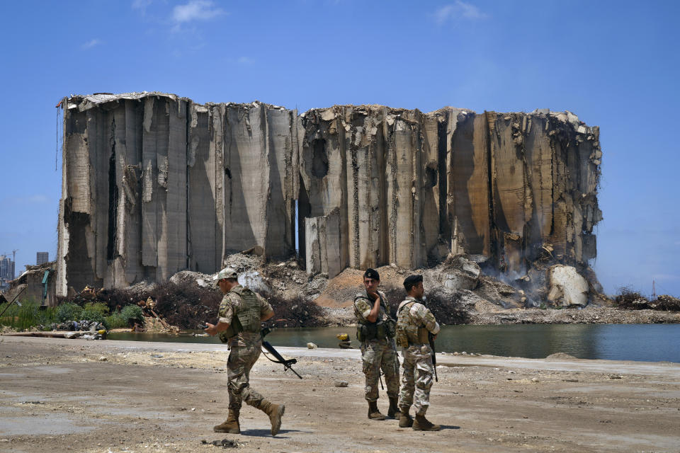 Lebanese army soldiers stand guard near grain silos that were damaged by the massive Beirut Port blast in August 2020, in Beirut, Lebanon, Thursday, July 14, 2022. Lebanese caretaker Economy Minister Amin Salam said Thursday that the capital's port silos, shredded in a massive blast two years ago may collapse, as authorities struggle to contain a fire. (AP Photo/Bilal Hussein)