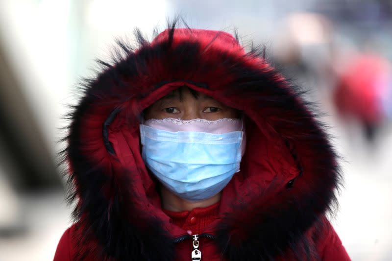 Woman wearing a mask is seen upon her arrival at Beijing West Railway Station in Beijing