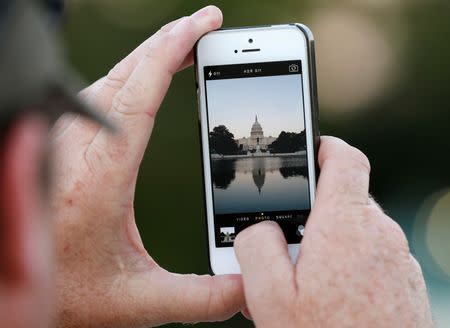 A man takes a photo of the U.S. Capitol in Washington September 30, 2013. REUTERS/Kevin Lamarque