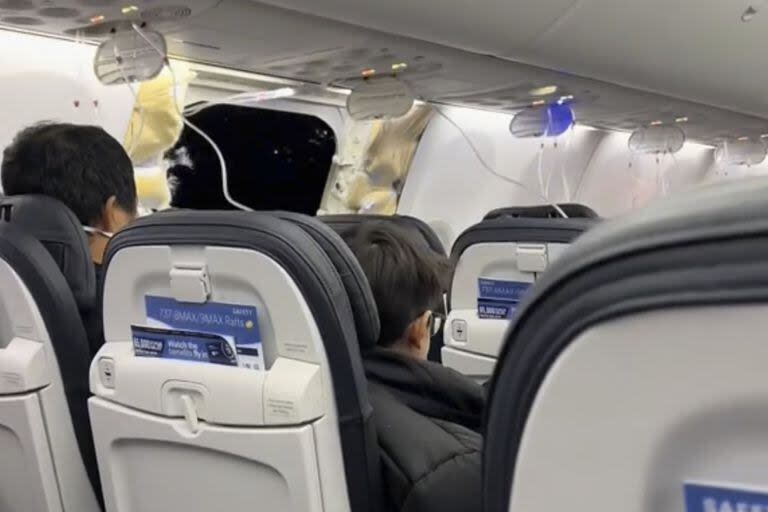 Esta imagen del video proporcionada por Elizabeth Le muestra a los pasajeros cerca de los daños en un Boeing 737 Max 9 de Alaska Airlines, vuelo 1282, que se vio obligado a regresar al Aeropuerto Internacional de Portland el viernes 5 de enero de 2024.