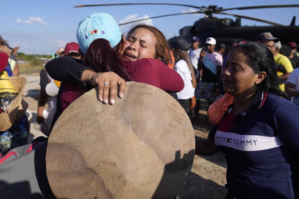 A woman cries, facing camera, as she receives a family member who was in Bulla Loca during a mine collapse, at the airport in La Paragua, Bolivar state, Venezuela, Thursday, Feb. 22, 2024. The collapse of an illegally operated open-pit gold mine in central Venezuela killed at least 14 people and injured several more, state authorities said Wednesday, as some other officials reported an undetermined number of people could be trapped. (AP Photo/Ariana Cubillos)