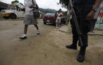 Students walk past a policeman guarding a school at an impoverished neighbourhood in Acapulco October 20, 2011. Teachers are demanding security from the government after they received extortion threats from suspected drug gangs, local media reported. REUTERS/Tomas Bravo (MEXICO - Tags: CRIME LAW)