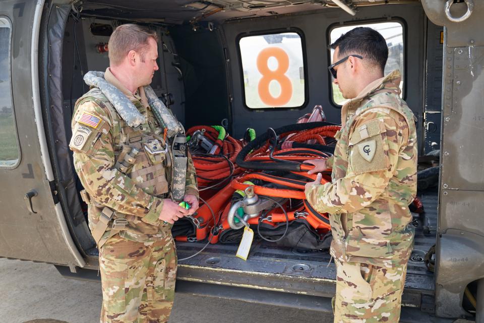 Brendan Young (left) and Daniel Bentley (right) from the National Guard show the fire buckets used to carry water on a UH-60 Black Hawk helicopter on Sunday.