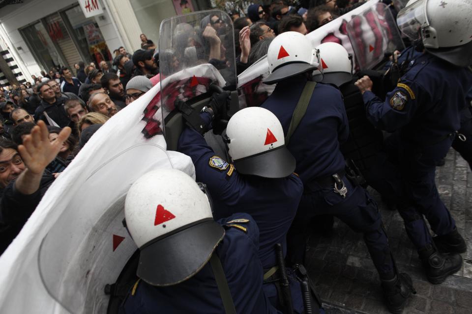 Riot policemen try to disperse demonstrators during a protest against the opening of shops on Sundays and the extension of working hours, in Athens' Ermou shopping street, on Sunday, April 13 2014. Fitch ratings agency warned the successful bond issue didn't mean an end to Greece's financial problems. In a report Friday it said the issue showed the country's progress but doesn't mean it will be able to finance itself on its own when the bailout program ends later this year. (AP Photo/Kostas Tsironis)