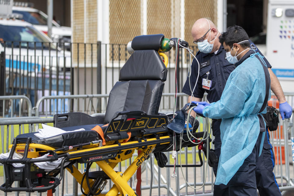 Emergency medical technicians disinfect their equipment after delivering a patient to Elmhurst Hospital Center, Saturday, April 4, 2020 in the Queens borough of New York. The new coronavirus causes mild or moderate symptoms for most people, but for some, especially older adults and people with existing health problems, it can cause more severe illness or death. (AP Photo/Mary Altaffer)