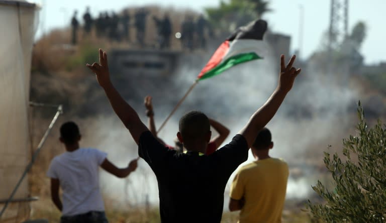 Palestinians gesture towards Israeli soldiers in the West Bank town of Tulkarem on October 8, 2015 following days of unrest