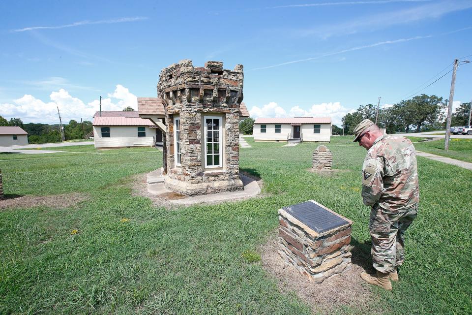 Fort Chaffee base commander Col. David Gibbons reads the inscription about Gate No. 5 that originally served at the west entrance to the base. That entrance was closed off in 1988 and the the building, called "the castles" on the base, was moved to served as a memorial to the World War II construction. Other markers on the site highlight that Fort Chaffee once housed refugees from Cuba in the early 1980s and Vietnam during that conflict.