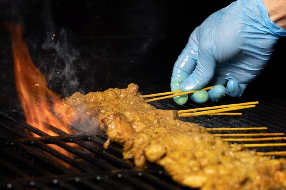 Grilling skewers of satay.