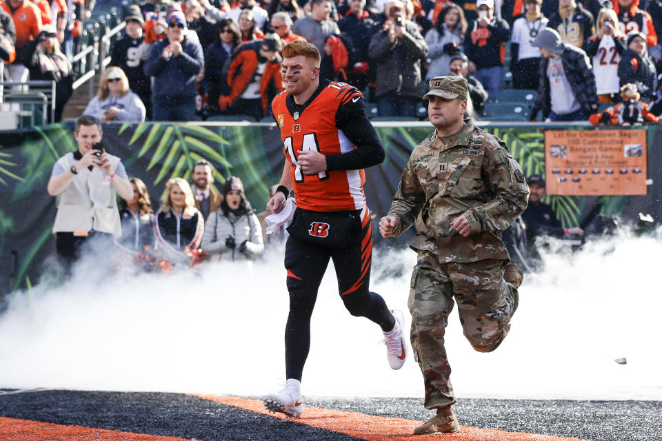 Cincinnati Bengals quarterback Andy Dalton (14) runs onto the field with a member of the armed forces before an NFL football game against the New Orleans Saints, Sunday, Nov. 11, 2018, in Cincinnati. (AP Photo/Frank Victores)