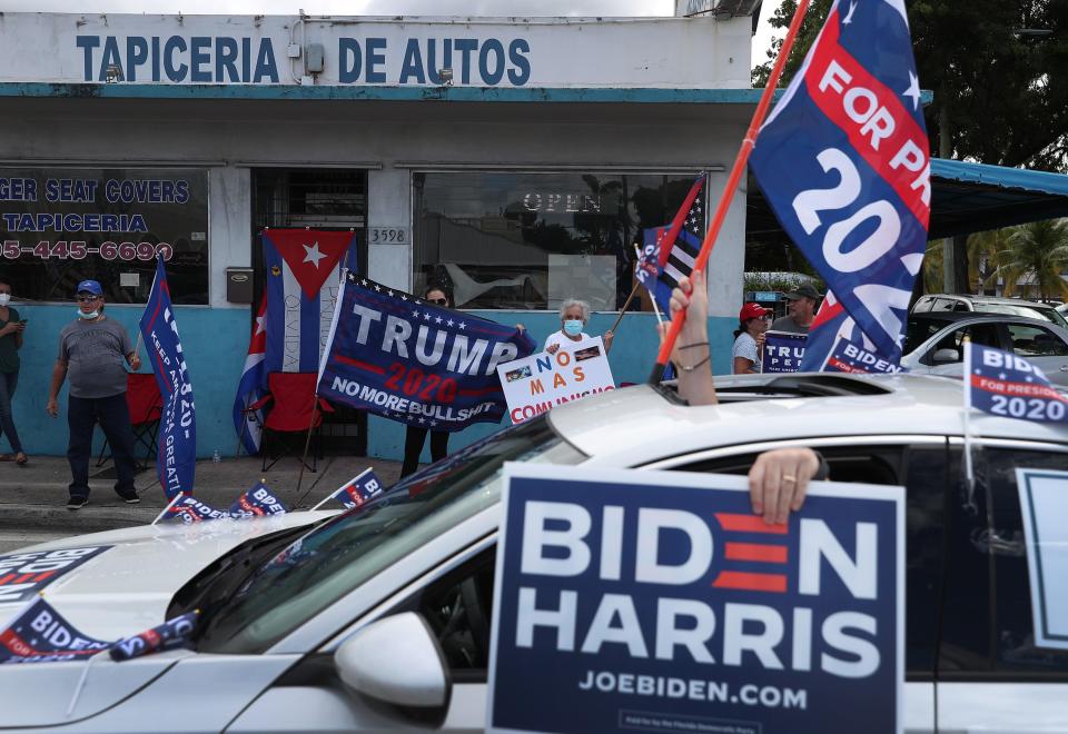 A caravan of supporters for Democratic presidential nominee Joe Biden drive past supporters of President Donald Trump standing on the sidewalk on October 18, 2020 in Miami, Florida.