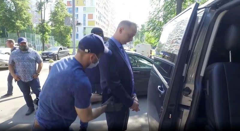 Ivan Safronov, a former journalist who works as an aide to the head of Russia's space agency Roscosmos, stands in front of a car while being detained in Moscow