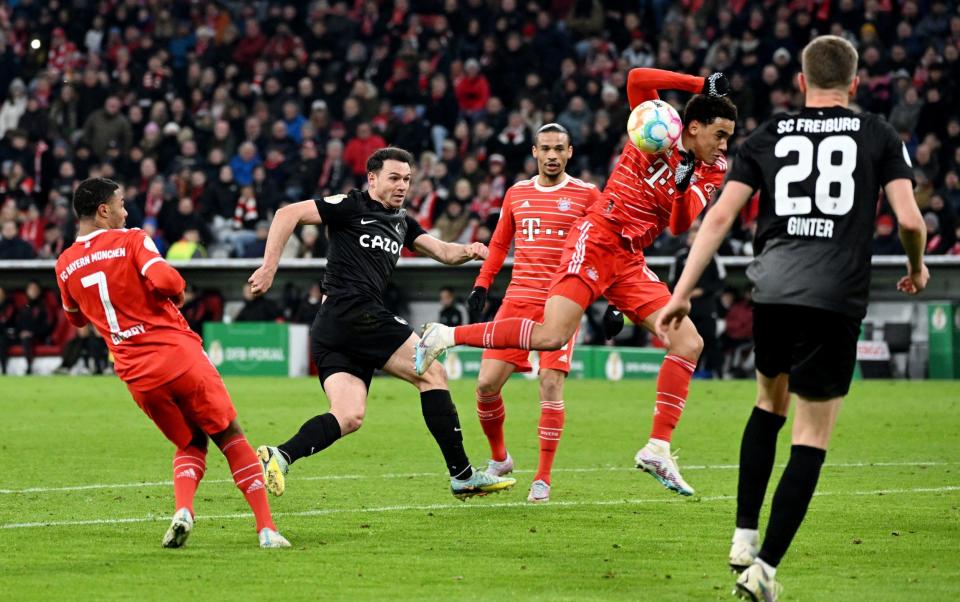 Nicolas Hofler del SC Freiburg dispara al arco mientras Jamal Musiala del Bayern Munich le da la mano - Reuters/Angelika Warmuth