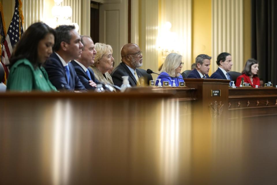 Nine House members sitting in a row in the front of a hearing room