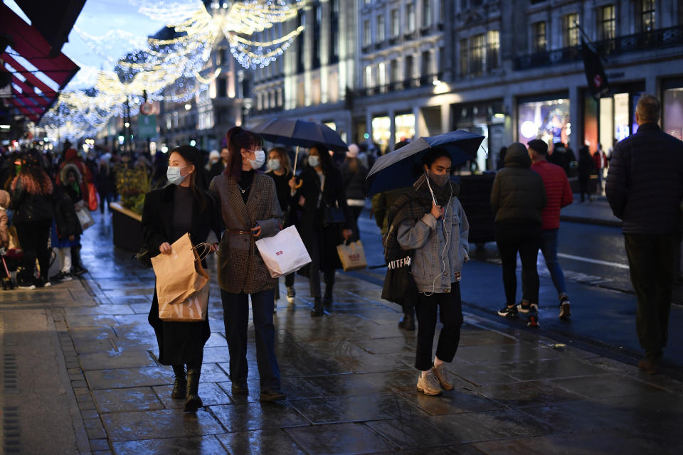 Shoppers wear face masks as they walk in Regent Street, ahead of the new Tier-4 restriction measures, in London, Saturday, Dec. 19, 2020. Britain's Prime Minister Boris Johnson says Christmas gatherings cannot go ahead and non-essential shops must close in London and much of southern England as he imposed a new, higher level of coronavirus restrictions to curb rapidly spreading infections.(AP Photo/Alberto Pezzali)