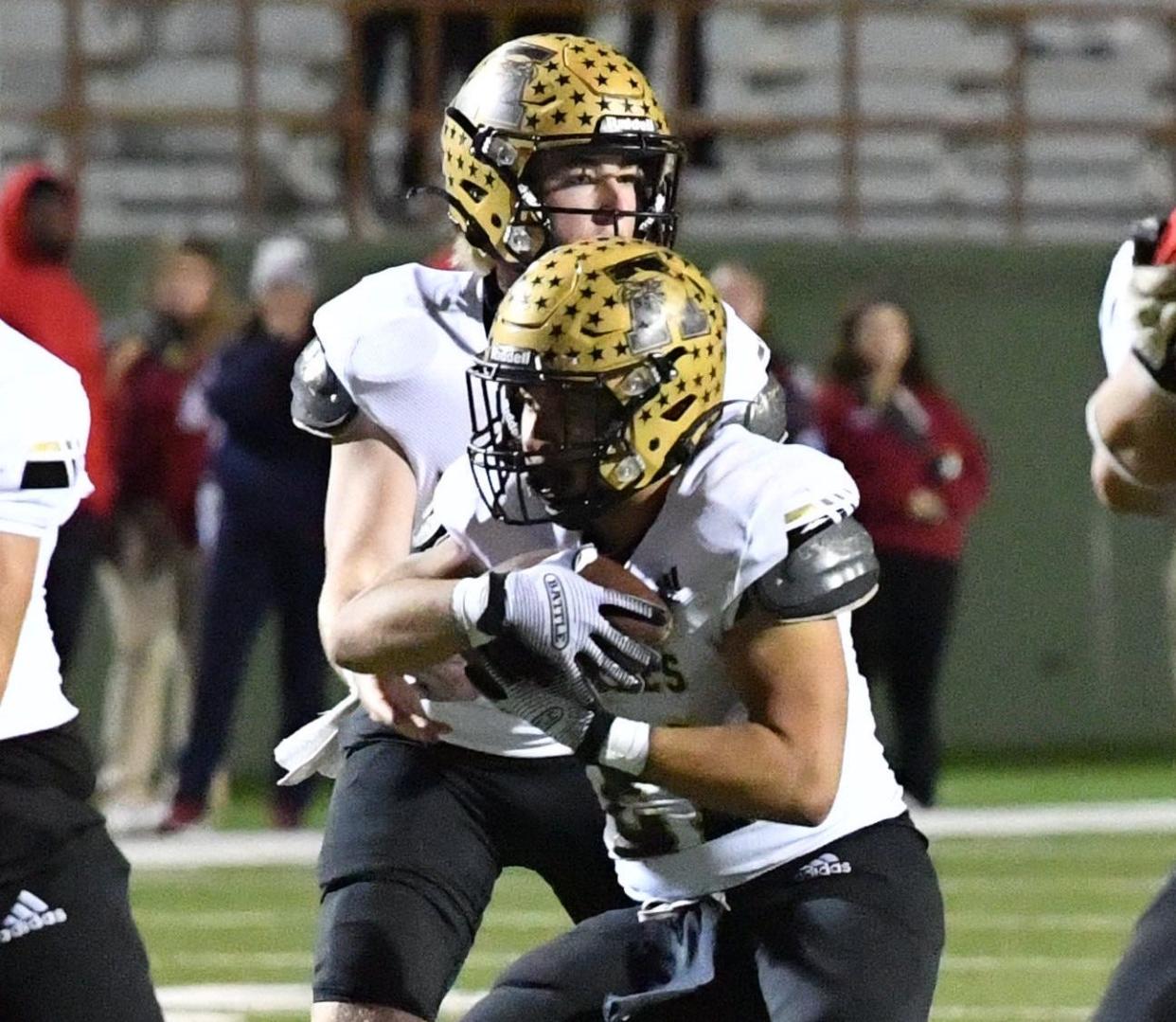 Abilene High's Dylan Slack hands the ball off to Chad Lara during a playoff game against Justin Northwest on Friday at Memorial Stadium.