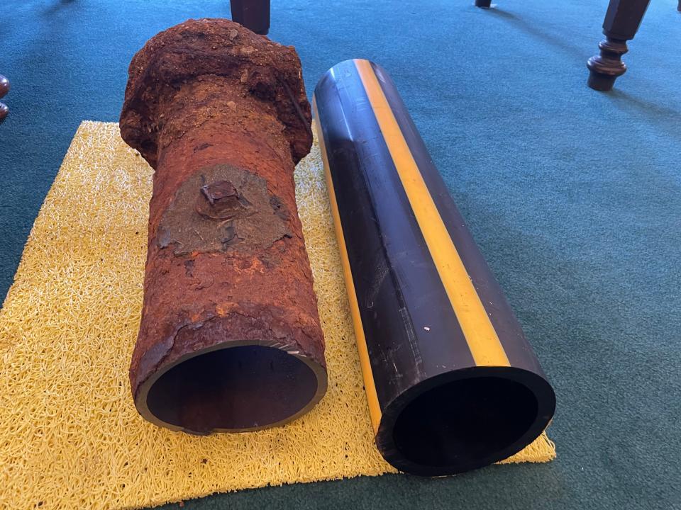 A cast iron pipe next to a polyethylene pipe.
