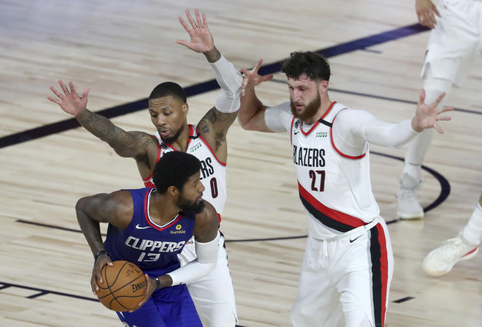 Los Angeles Clippers guard Paul George (13) looks to pass as Portland Trail Blazers guard Damian Lillard (0) and center Jusuf Nurkic (27) defend during the second half in an NBA basketball game Saturday, Aug. 8, 2020, in Lake Buena Vista, Fla. (Kim Klement/Pool Photo via AP)
