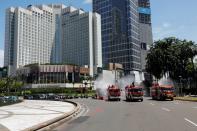 Firefighters spray disinfectant using high pressure pump trucks to prevent the spread of coronavirus disease (COVID-19), on the main road in Jakarta