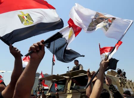 People cheer while carrying national flags in front of a military convoy passing by to secure central cairo as they gather in Tahrir square to celebrate an extension of the Suez Canal, Cairo, Egypt, August 6, 2015. REUTERS/Mohamed Abd El Ghany