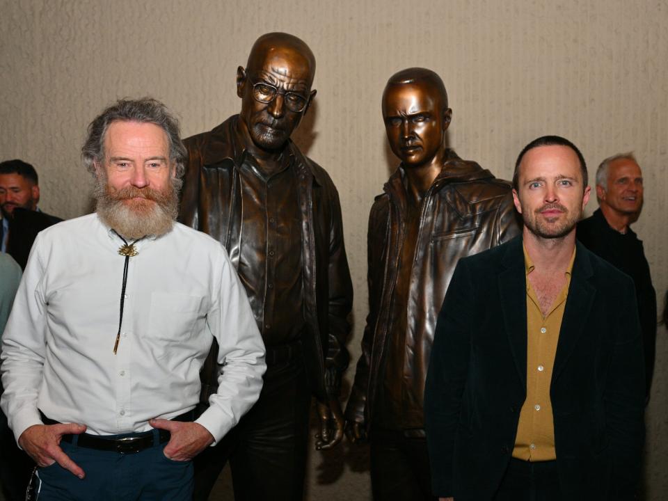 Bryan Cranston and Aaron Paul posing with bronze statues of their "Breaking Bad" characters in July 2022.