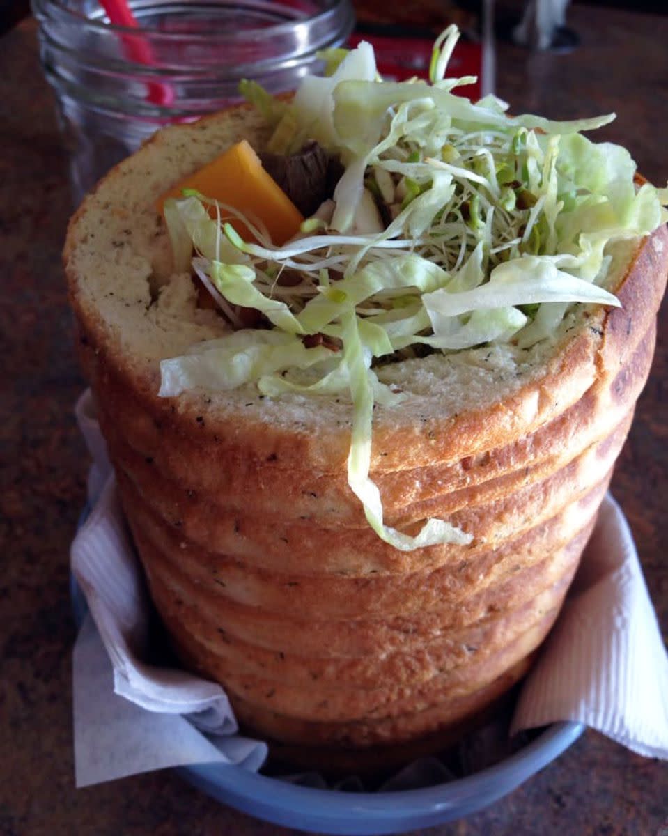 Closeup of The Clubfoot Sandwich surrounded by white napkins, Staggering Ox, Helena, Montana, a drink behind it on a table