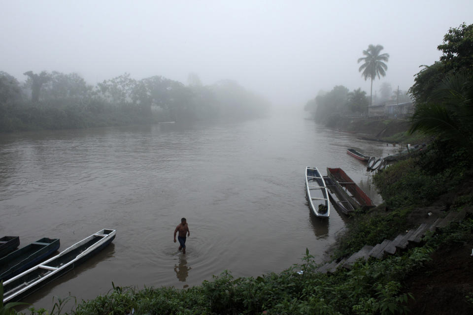 FILE - In this June 22, 2012, file photo, a man bathes in a river at dawn in the Darien Province on the border with Colombia, in Union Choco, Panama. The area is known as the Darien Gap, a 60-mile (97-kilometer) stretch of roadless jungle straddling the border of Colombia and Panama. One man's journey to America from his home in Mauritania was a dangerous and arduous one that took him through the Darien Gap. (AP Photo/Arnulfo Franco, File)