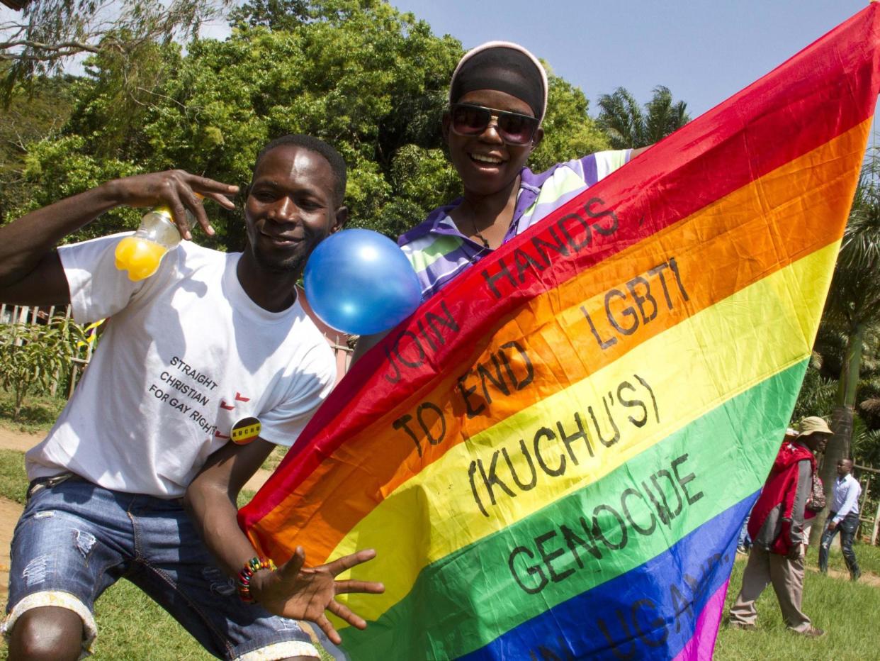 Ugandan men hold a rainbow flag reading 'Join hands to end LGBTI (called Kuchu in Uganda) genocide': ISAAC KASAMANI/AFP/Getty Images