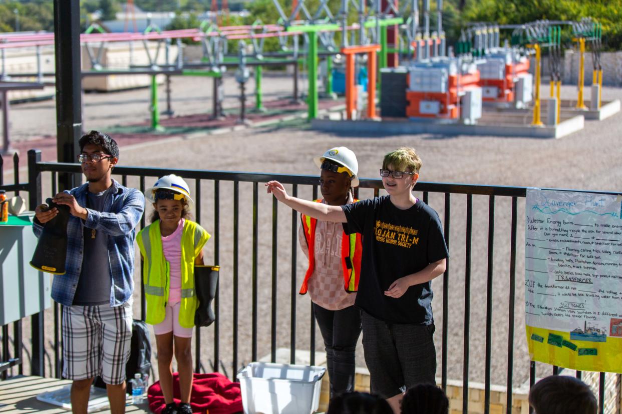 TCALC Teaching as a Profession students Misael Hernandez, left, and Icarus Franklin, right, teach about the various safety items electric lineman wear on the job, with Meadows Elementary fourth-graders Ma'Leah Johnson and Kemoni Glover helping demonstrate.