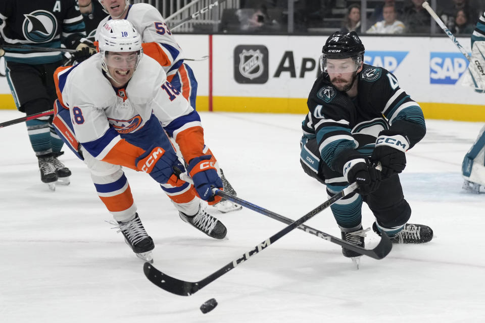San Jose Sharks defenseman Kyle Burroughs, right, reaches for the puck next to New York Islanders left wing Pierre Engvall (18) during the second period of an NHL hockey game in San Jose, Calif., Thursday, March 7, 2024. (AP Photo/Jeff Chiu)